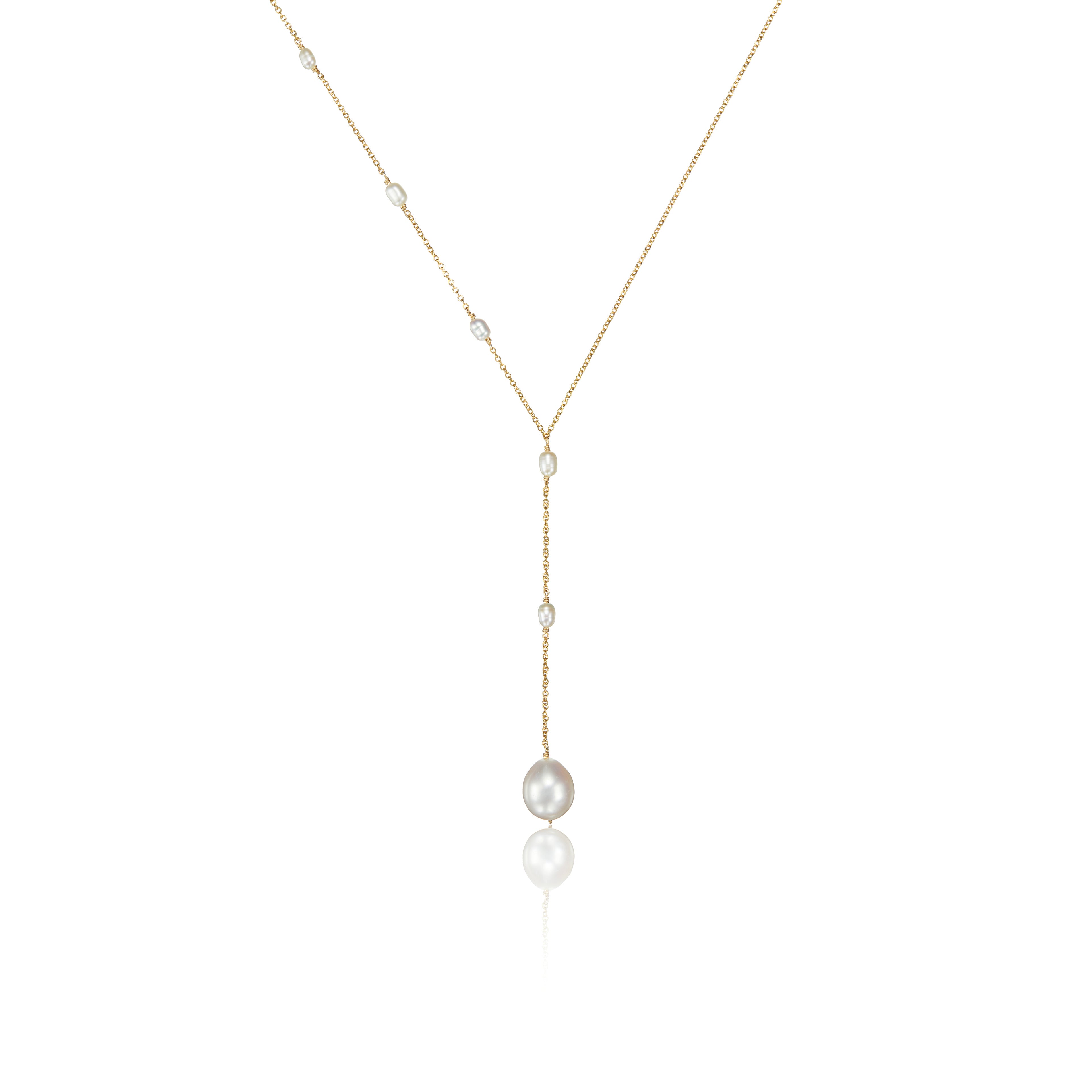 Gold seed pearl lariat necklace on a white background