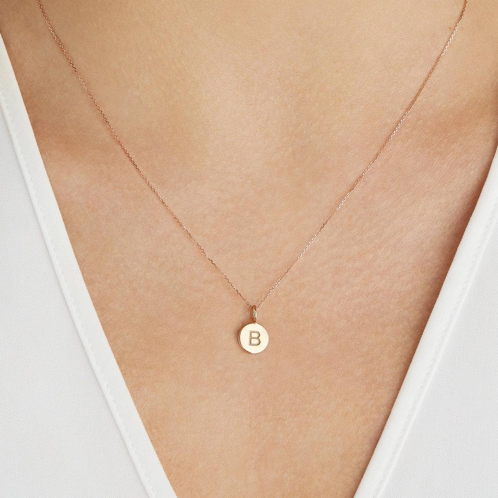 Gold small personalised disc necklace with the letter 'B' engraved worn on a chest with a white V neck top
