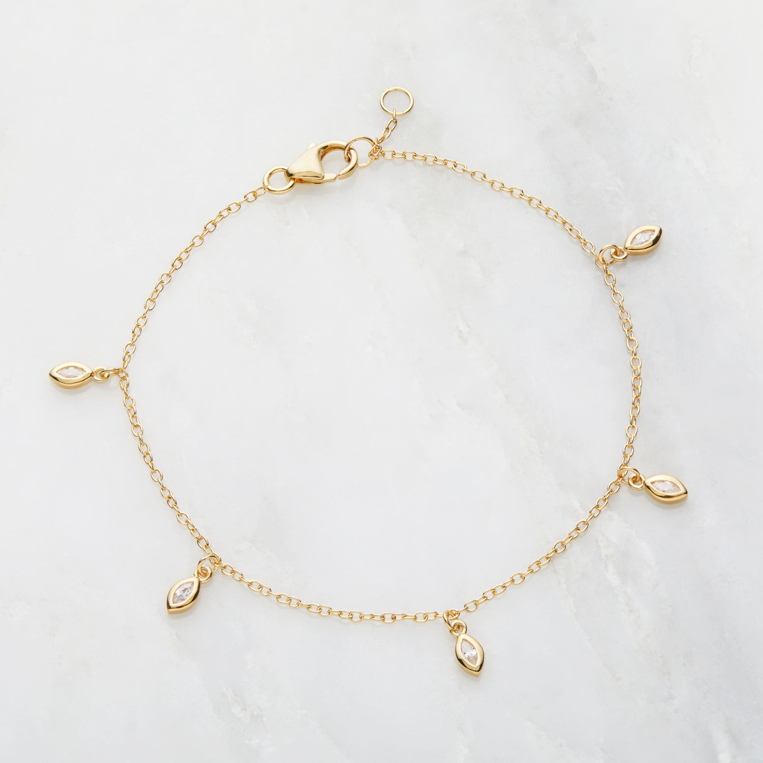 Gold diamond style marquise drop bracelet on a marble surface