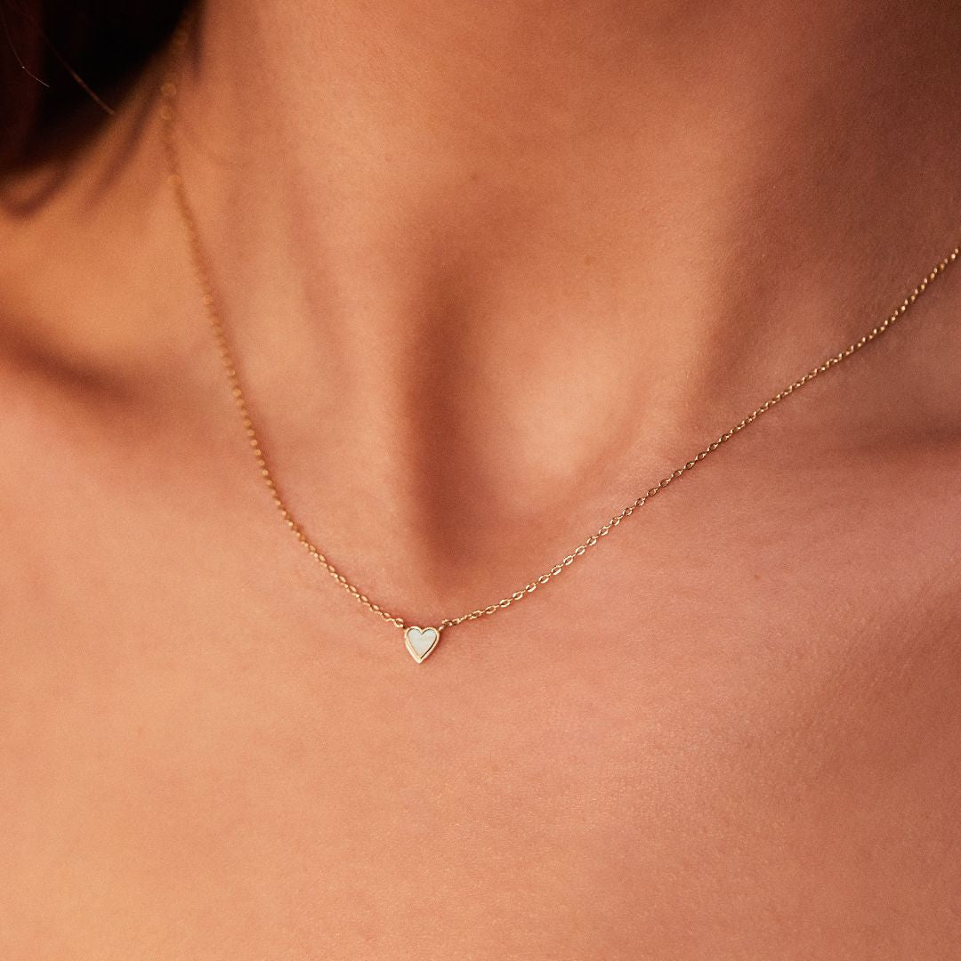 Gold tiny heart necklace around a neck