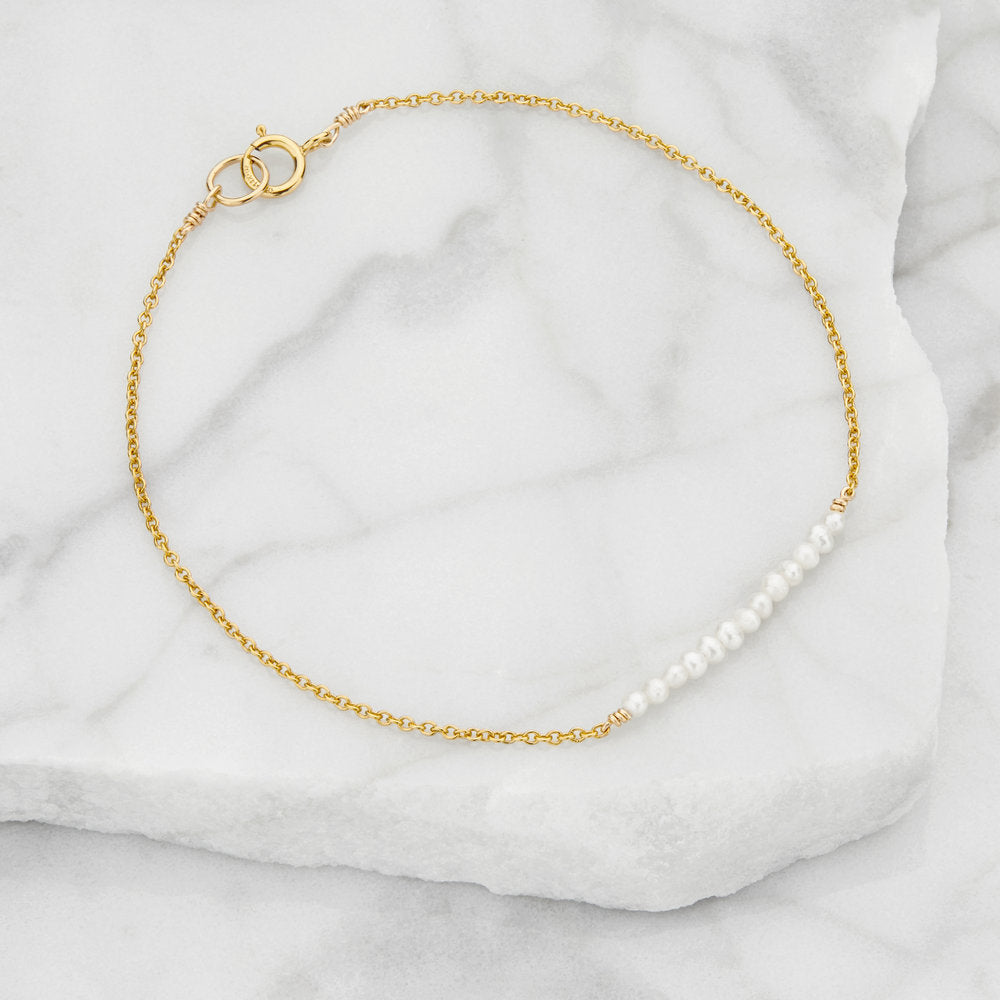 Gold small pearl cluster bracelet on marble surfaces