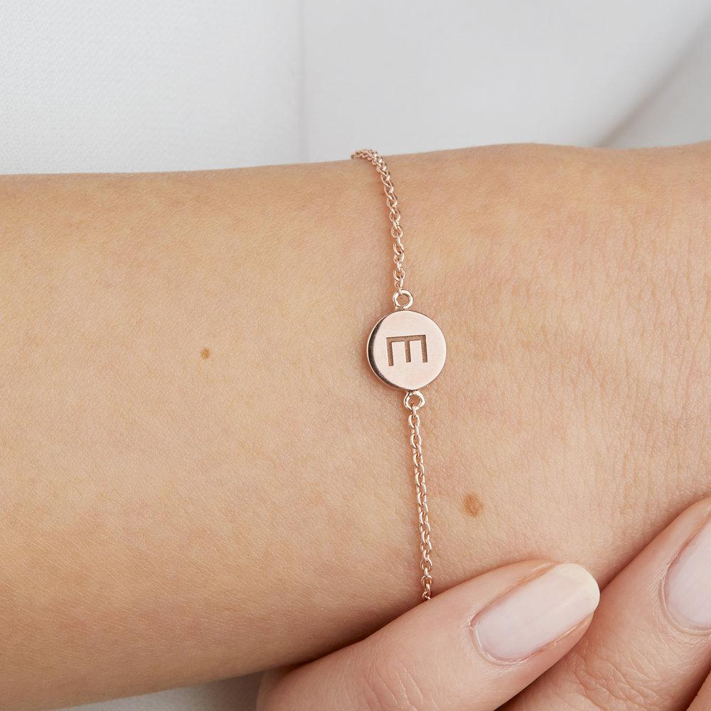 Rose gold personalised disc bracelet with the letter 'E' engraved on a wrist close up