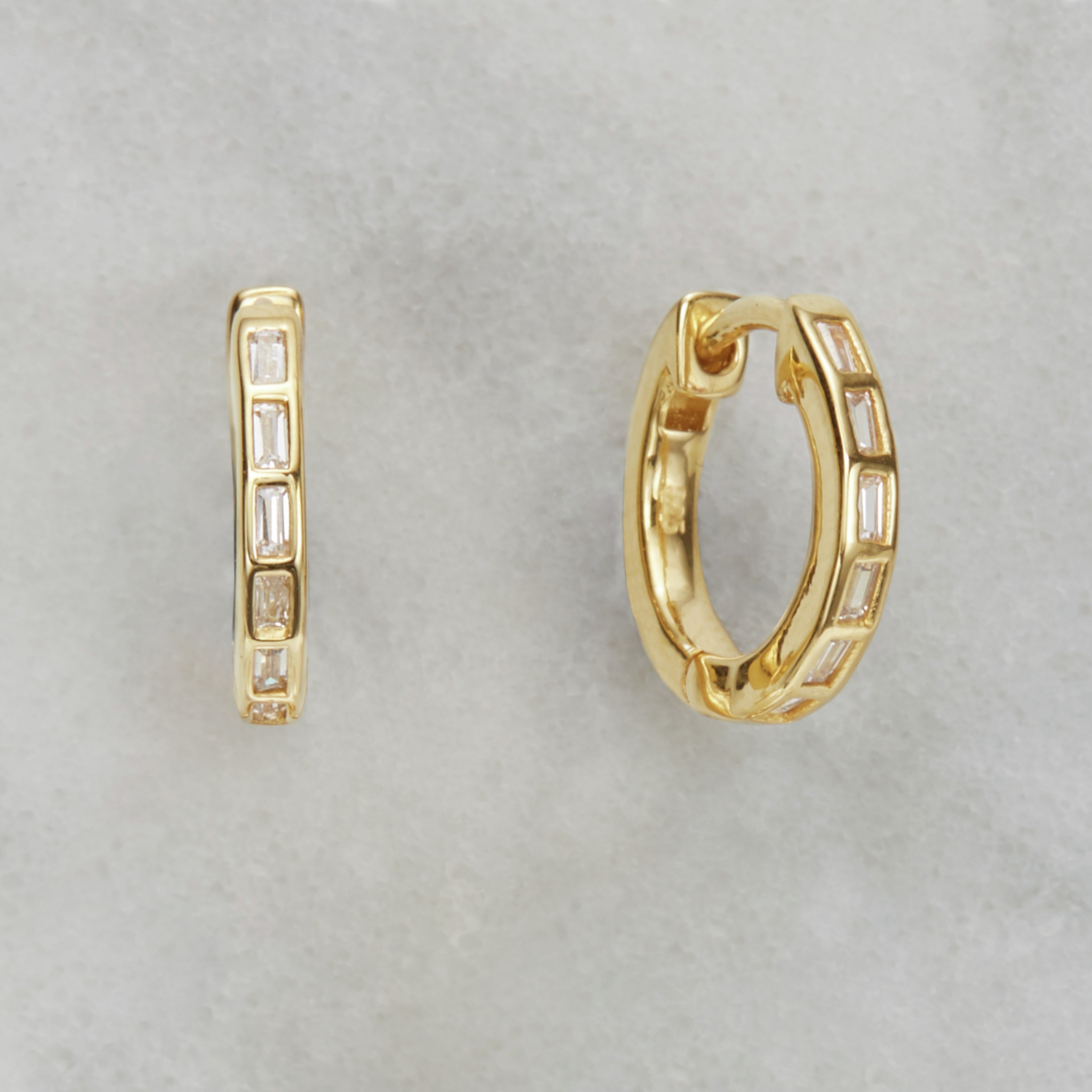 Gold diamond style baguette medium hoop earrings on a marble surface