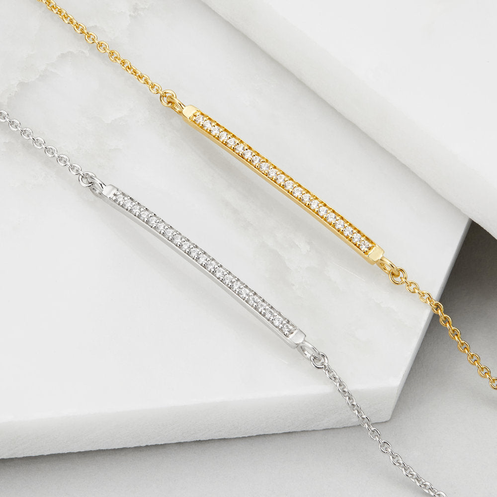 Gold diamond style bar bracelet with silver diamond style bar bracelet on marble surface