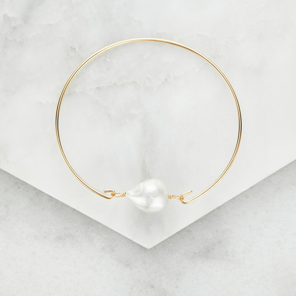 Baroque gold bangle with pearl on envelope background