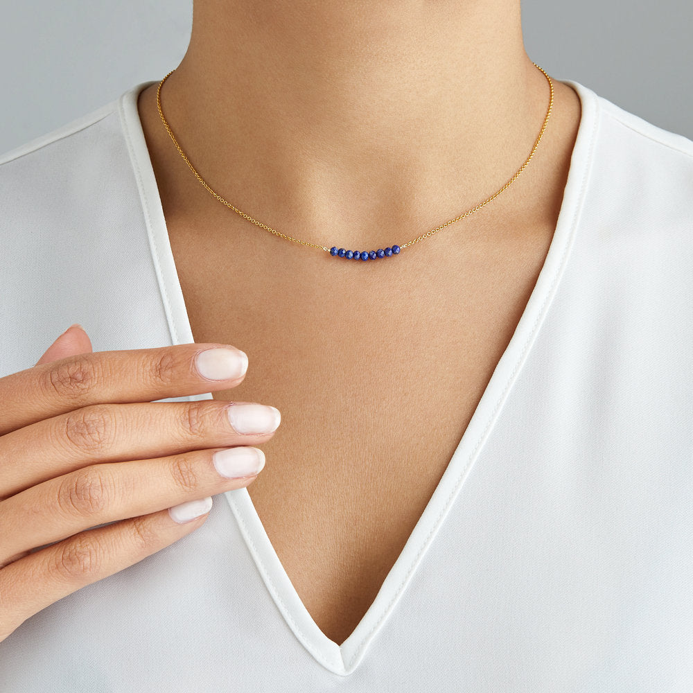 Gold lapis gemstone cluster choker around a neck with a white v neck top