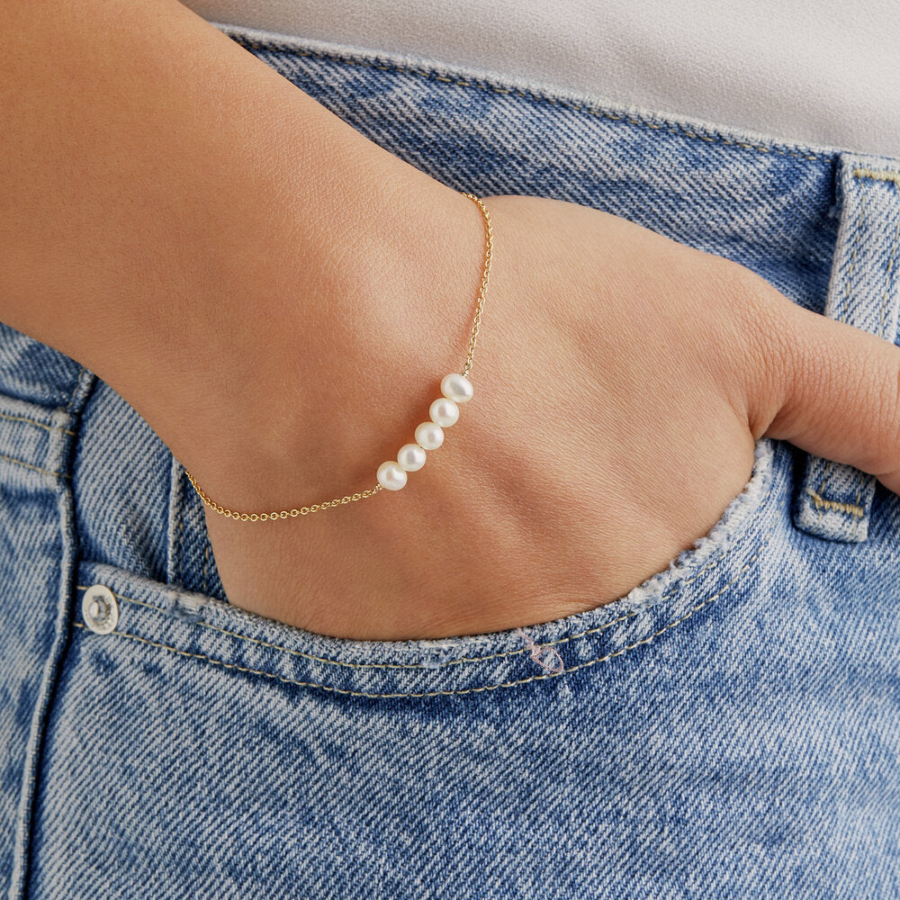 Gold cluster pearl bracelet on a wrist in a jean pocket
