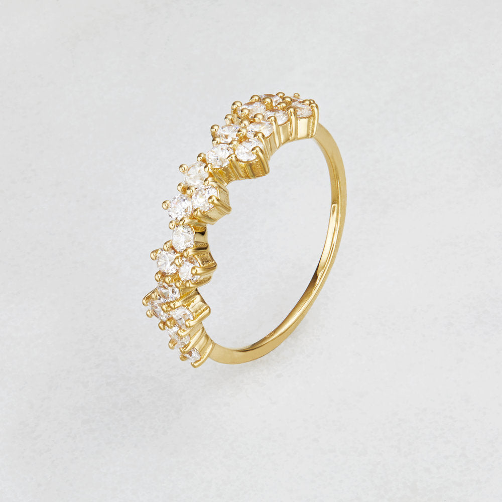 Gold diamond style cluster ring on a white surface at an angle