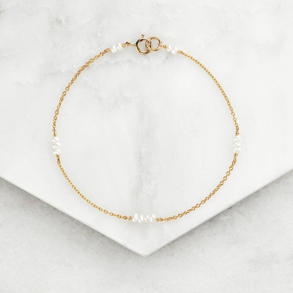 Gold mini pearl bracelet on marble surfaces