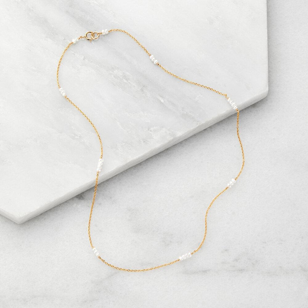Gold mini pearl choker on marble surfaces