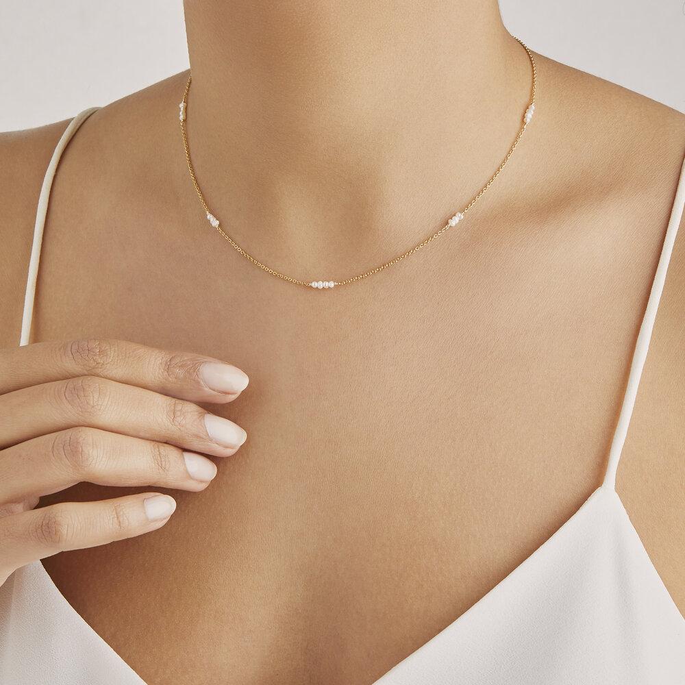 Gold mini pearl choker around a neck with white top