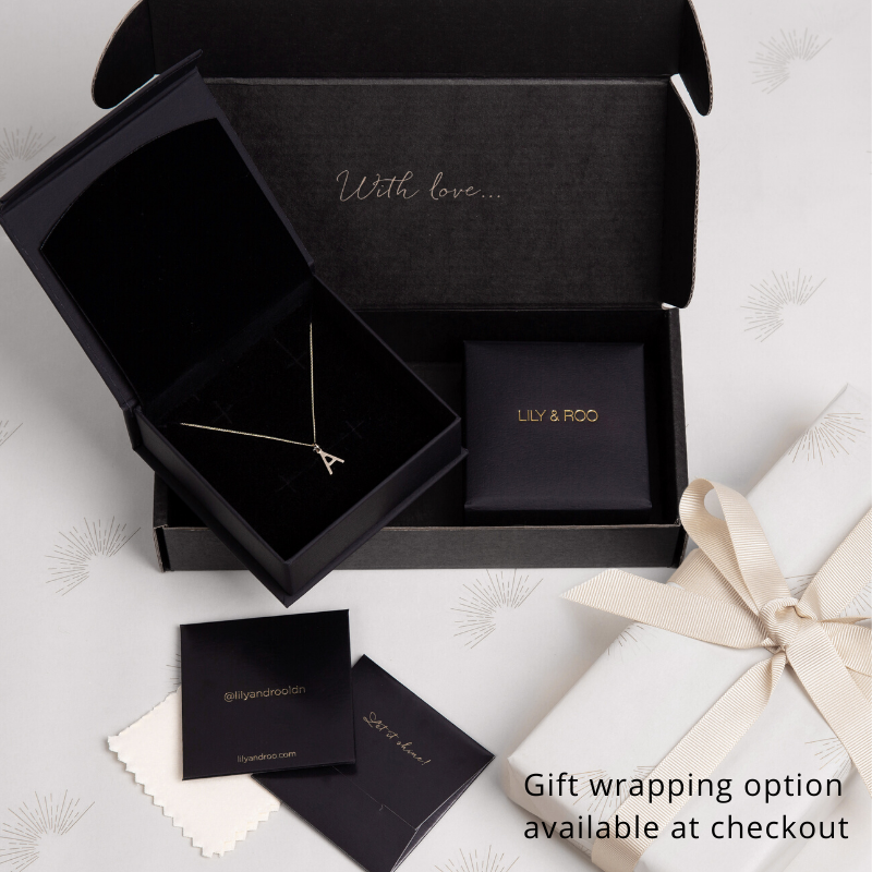 black gift wrapping jewellery boxes with an A letter necklace on a white background