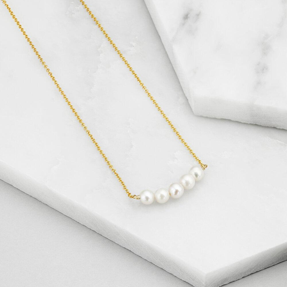 Gold pearl cluster necklace on marble surfaces