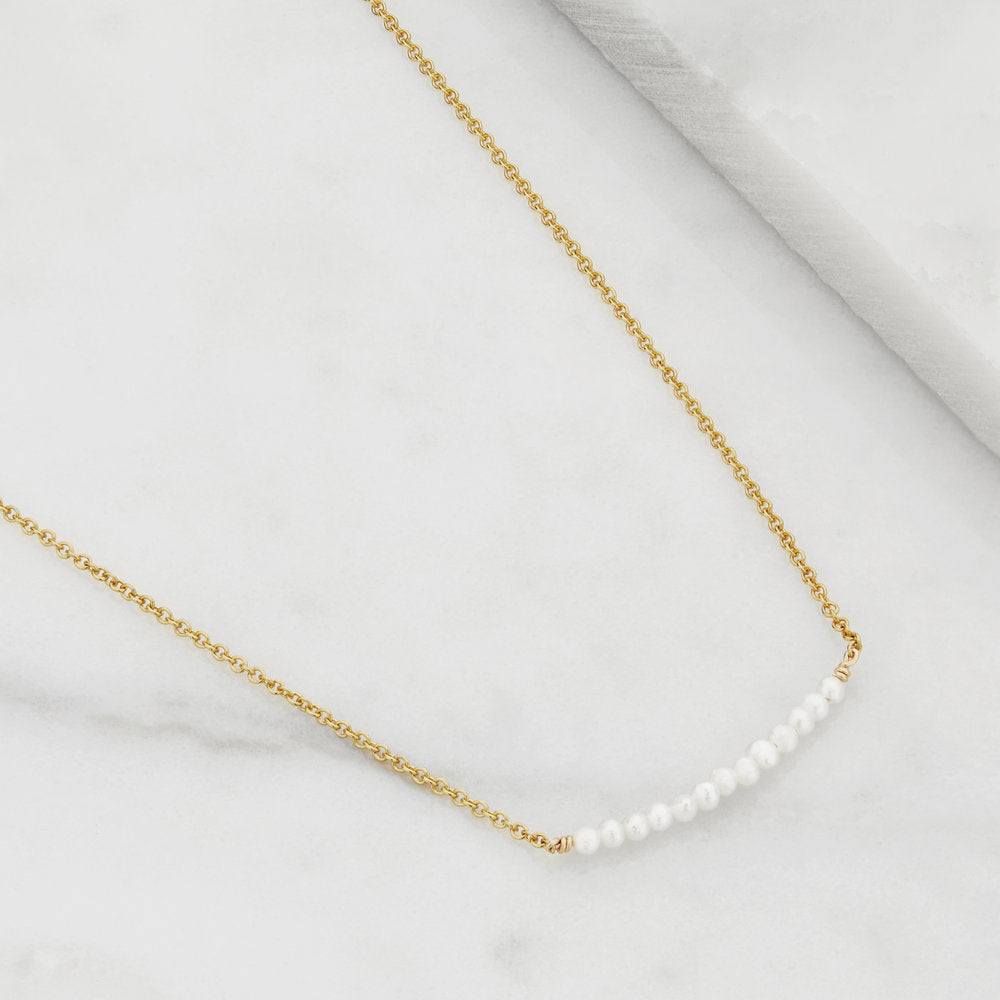 Gold small pearl cluster choker on a marble surface