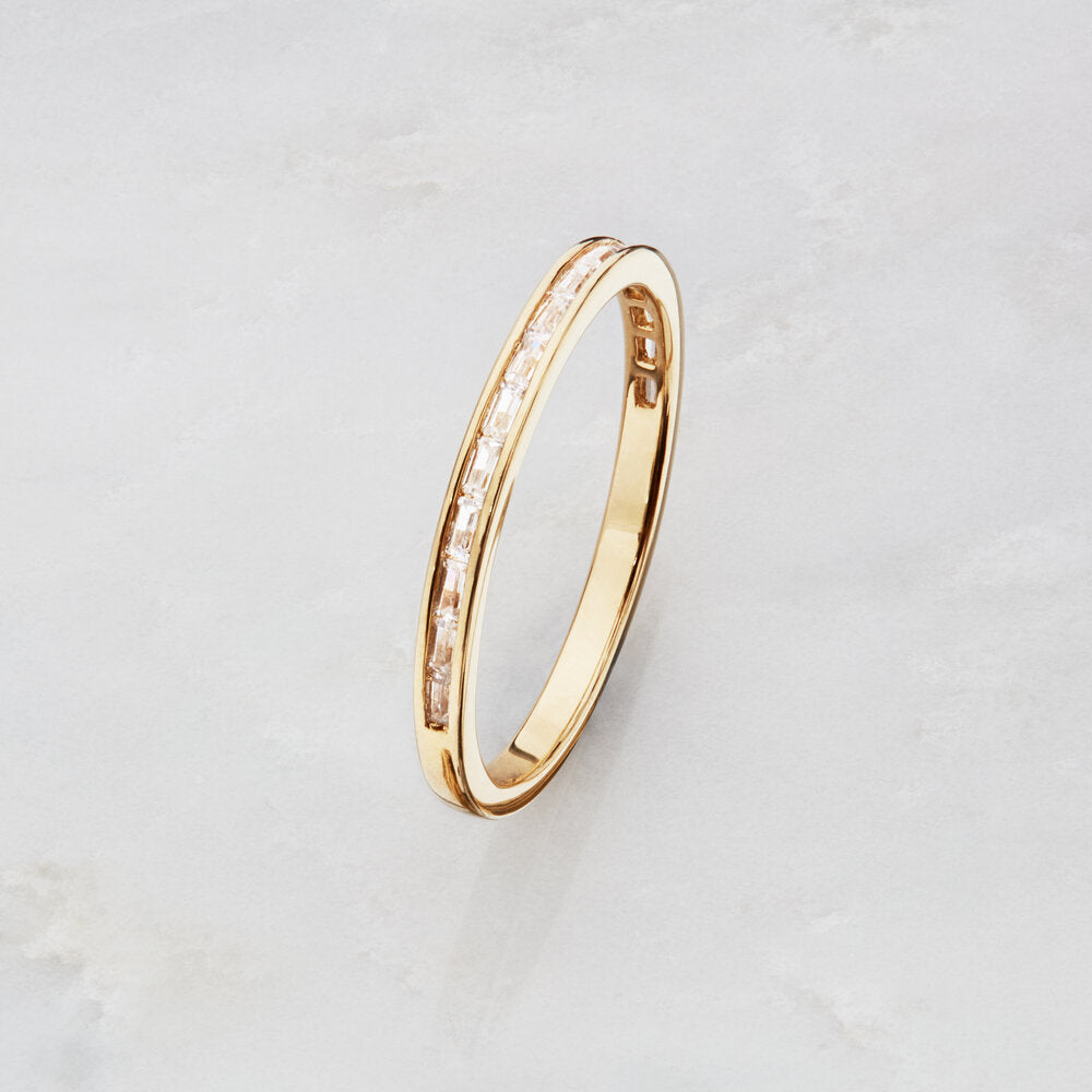Gold diamond style baguette eternity ring on a marble surface