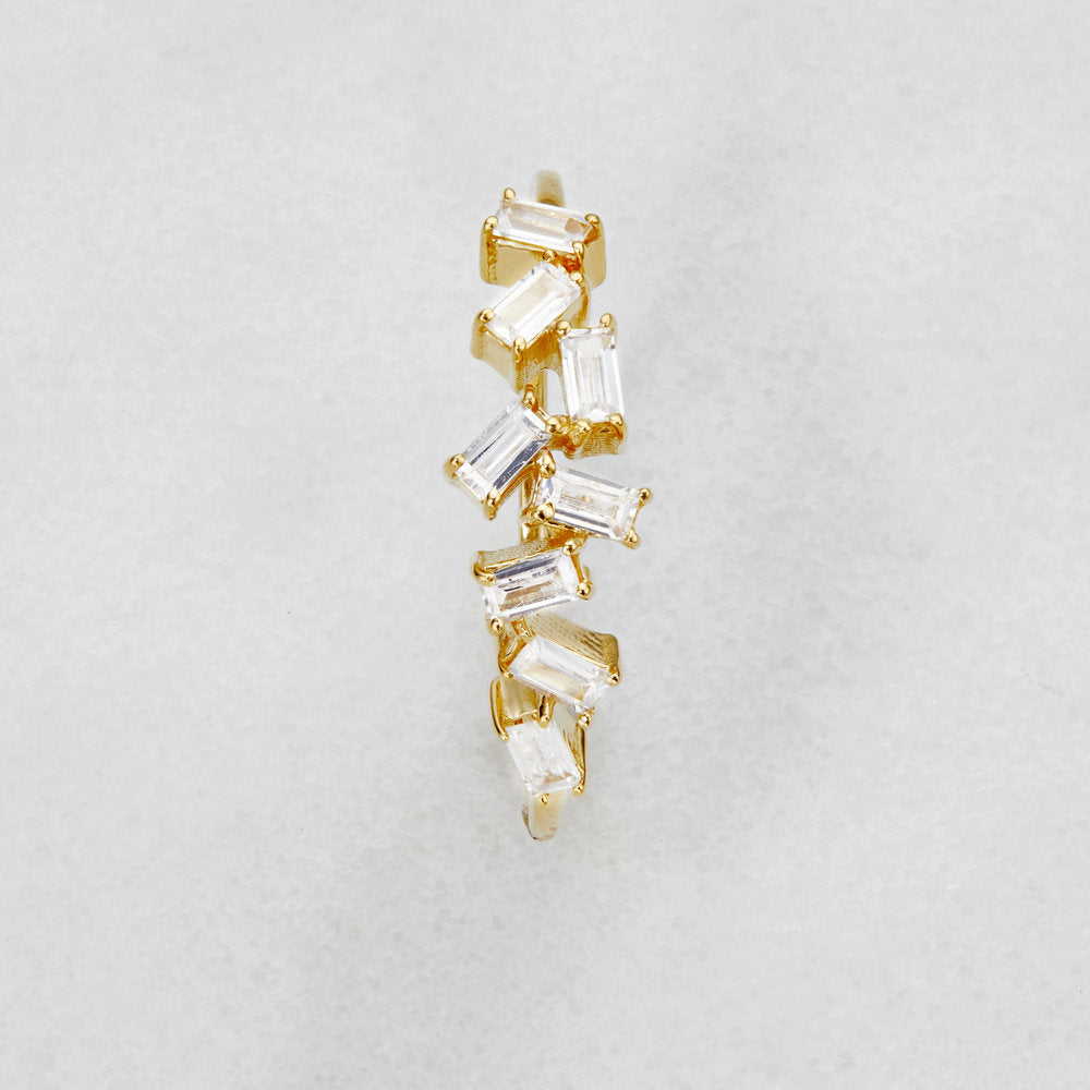 Birds-eye-view of a gold diamond style baguette ring on a white surface