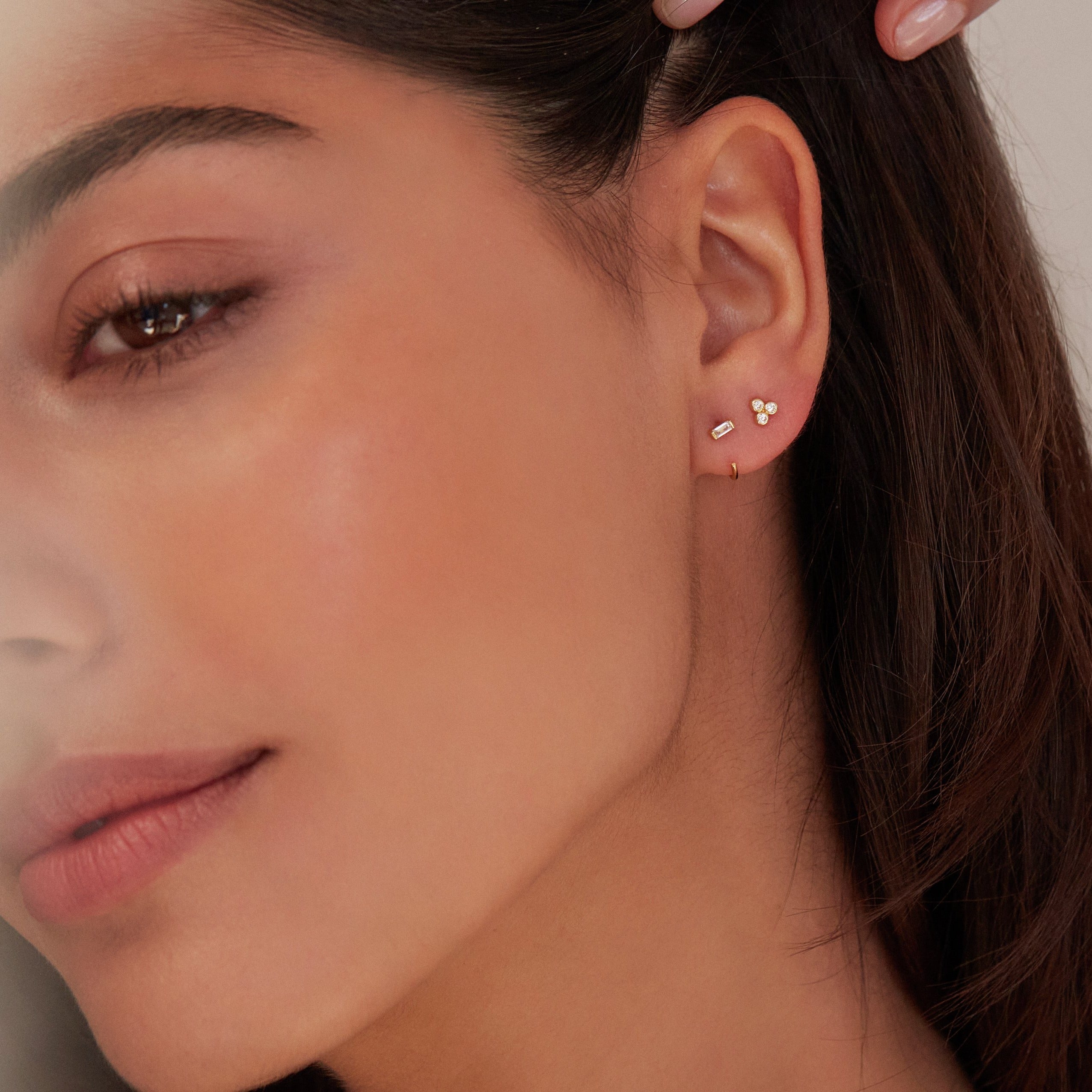 Gold diamond style baguette lobe hoop earring with gold diamond style pyramid stud earring in one ear lobe 