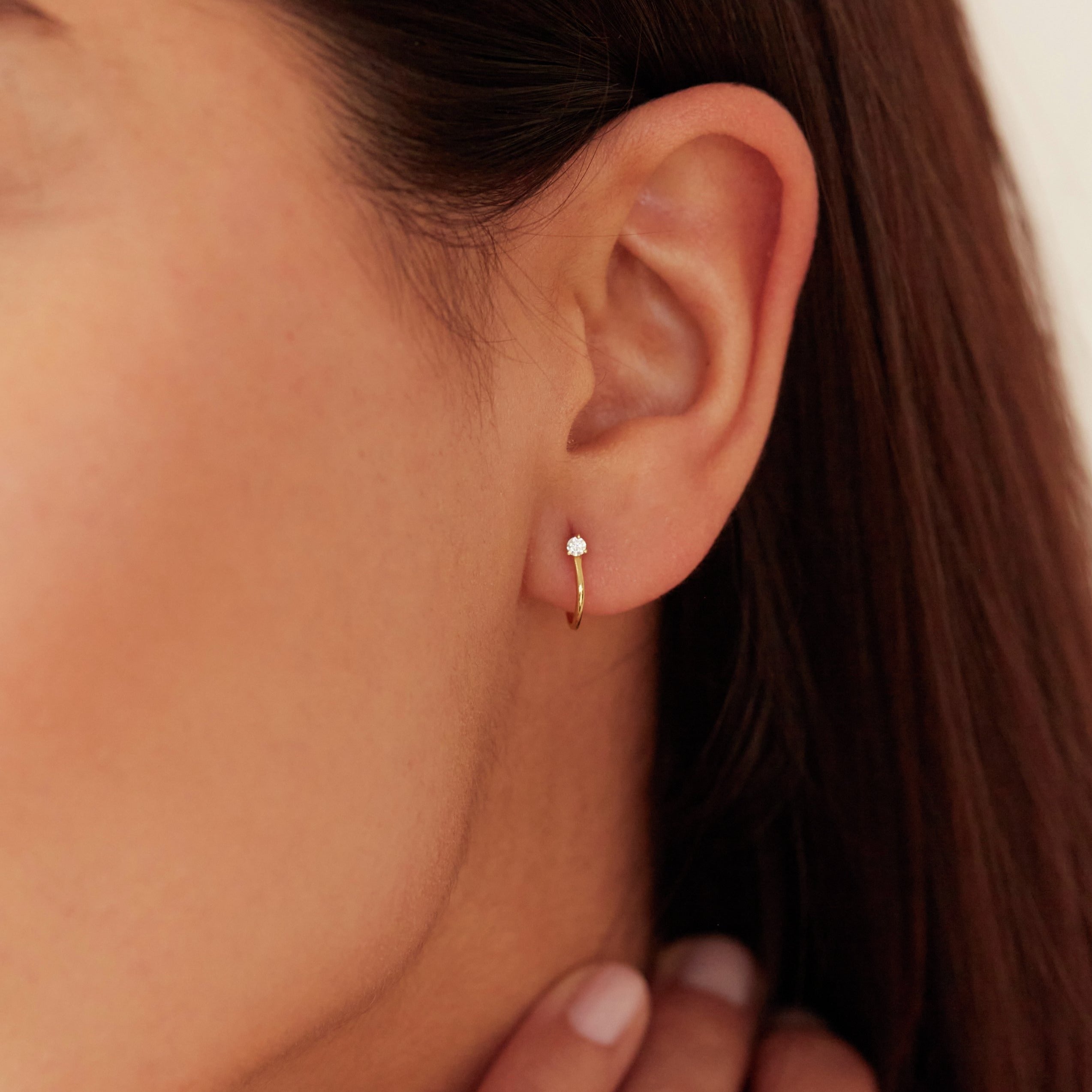 Gold diamond style lobe hoop stud earring in one ear lobe