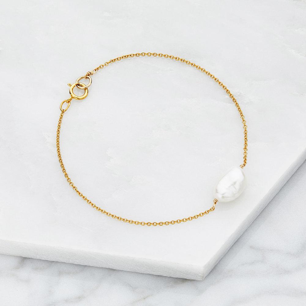 Gold large pearl bracelet on marble surfaces