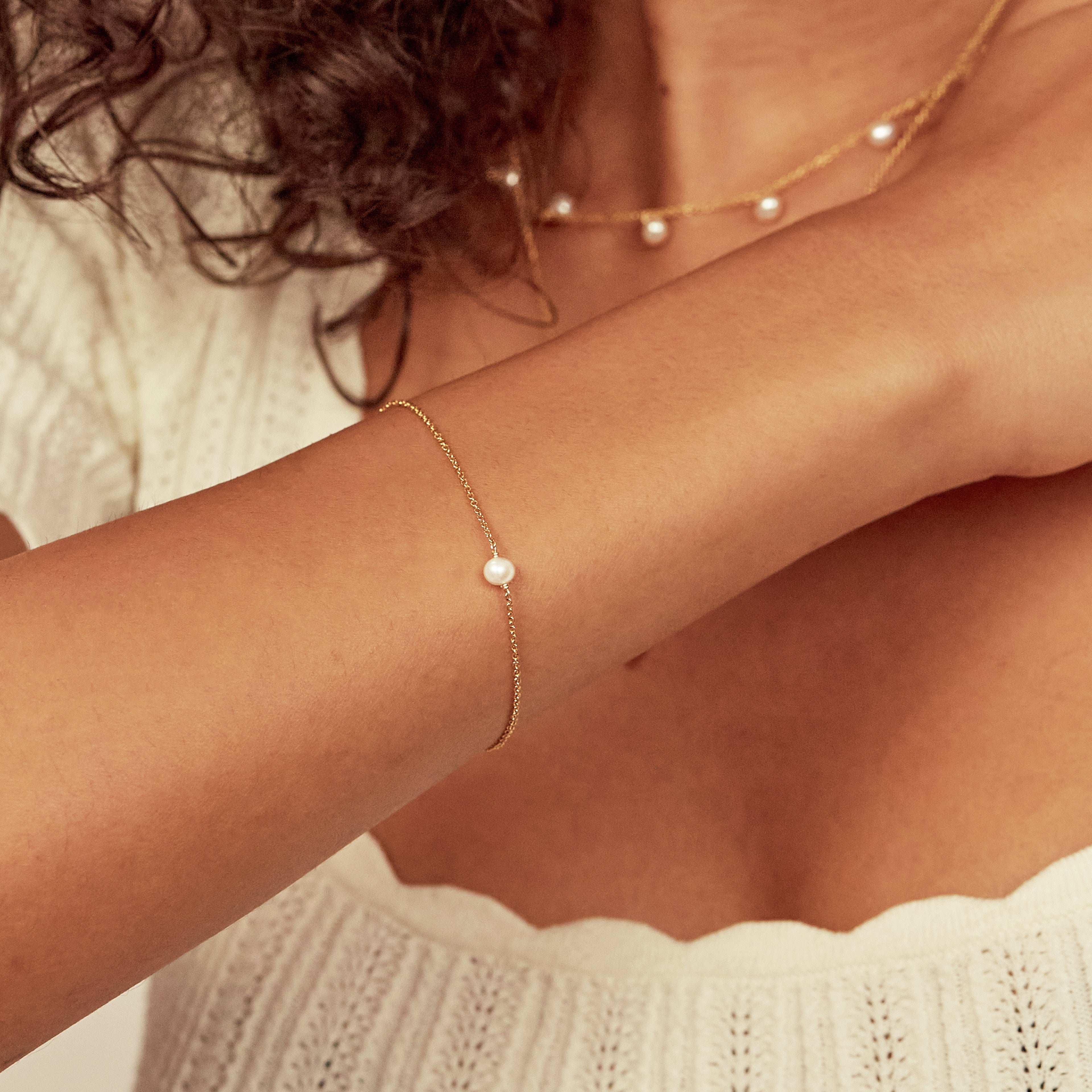 Gold single pearl bracelet on a wrist close up