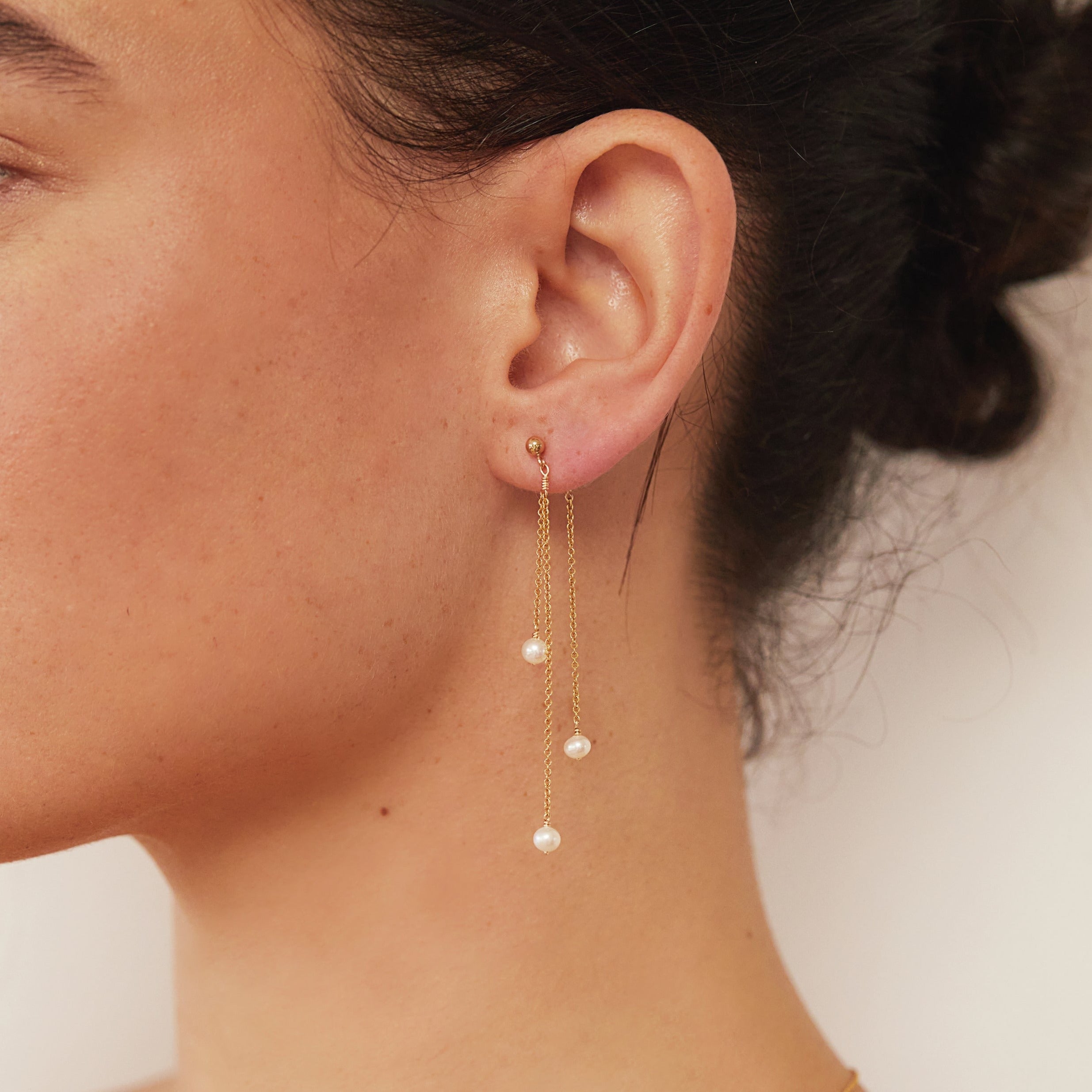 Gold layered pearl drop earring in one ear lobe