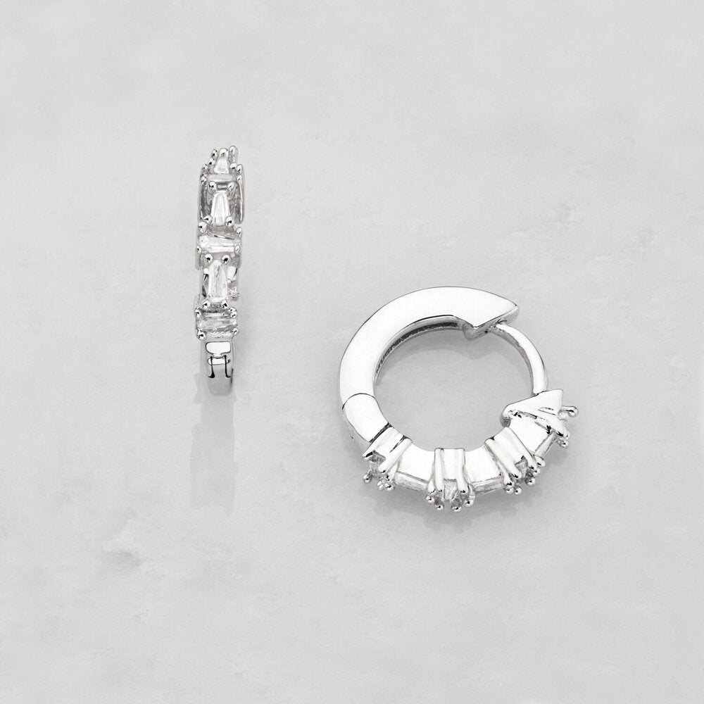 Silver diamond style baguette huggie hoop earrings on a marble surface