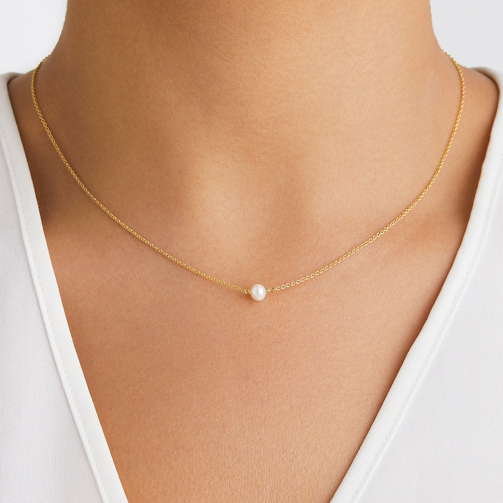 Gold single pearl choker around a neck
