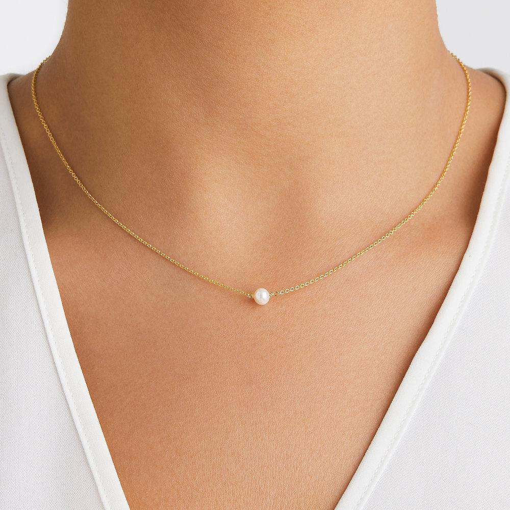 Gold single pearl choker around a neck