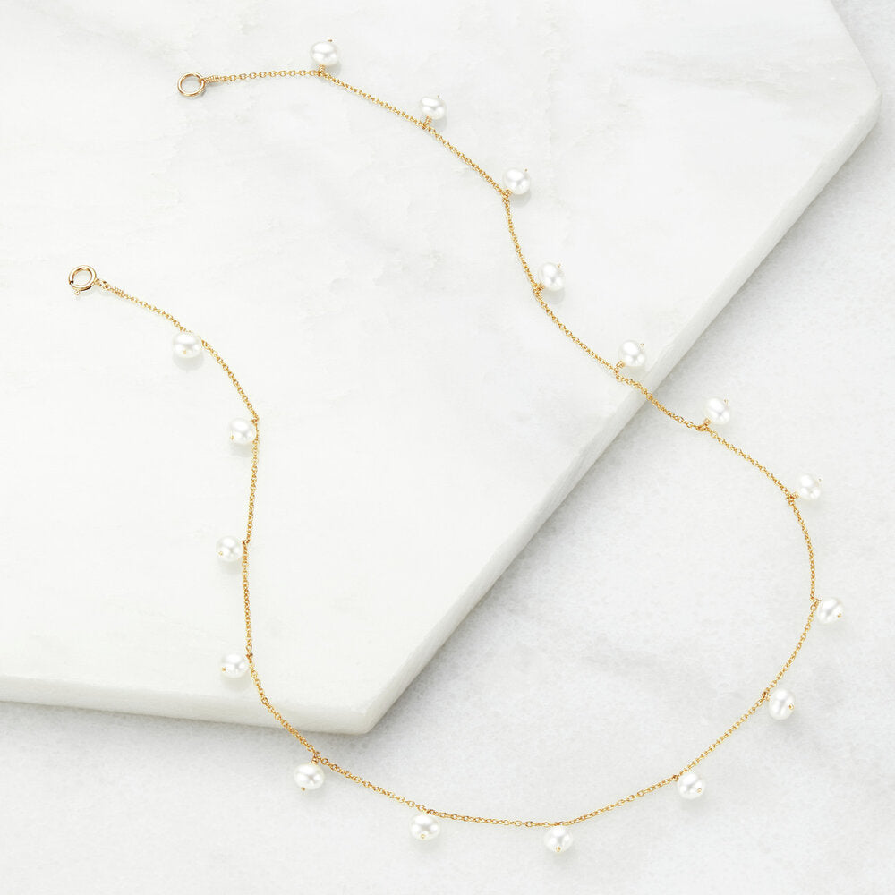 Gold pearl drop choker on marble surfaces