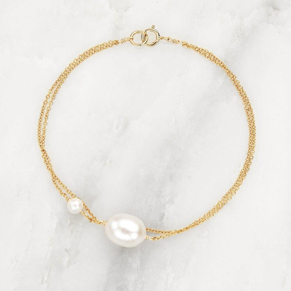 Gold layered large and small pearl bracelet on marble surface