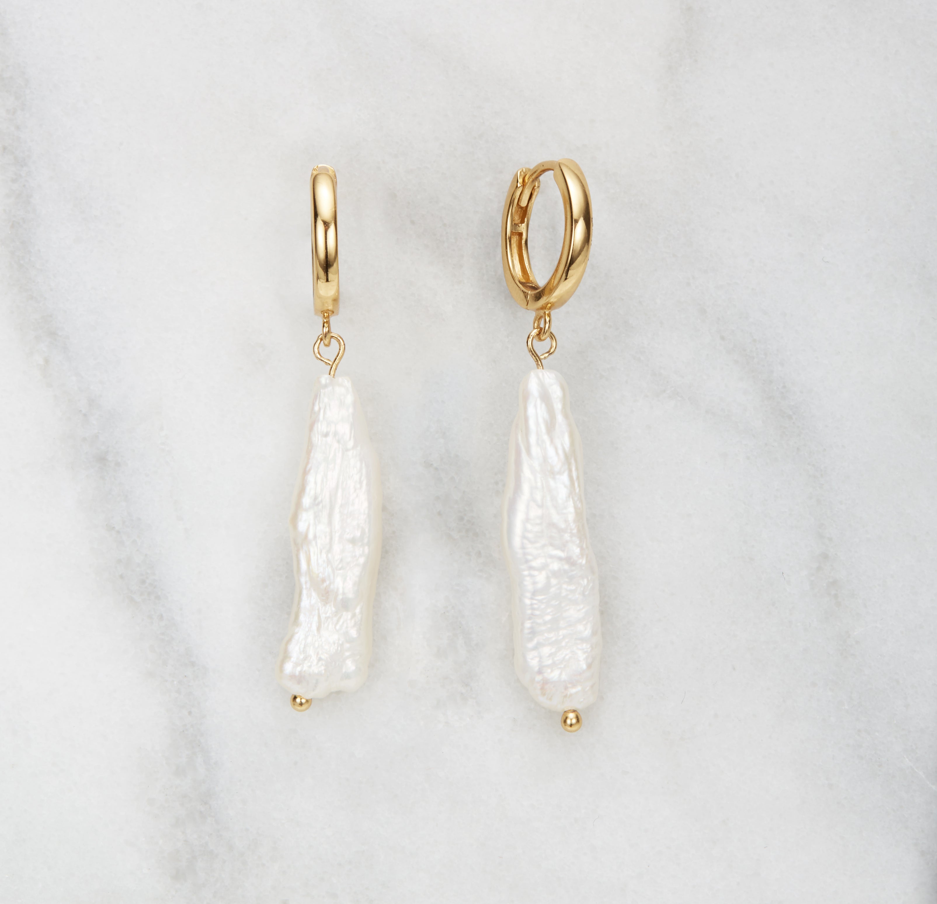 gold baroque pearl shard hoop earrings on a white marble background