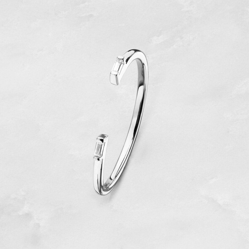 A silver diamond style baguette gap ring on a marble surface