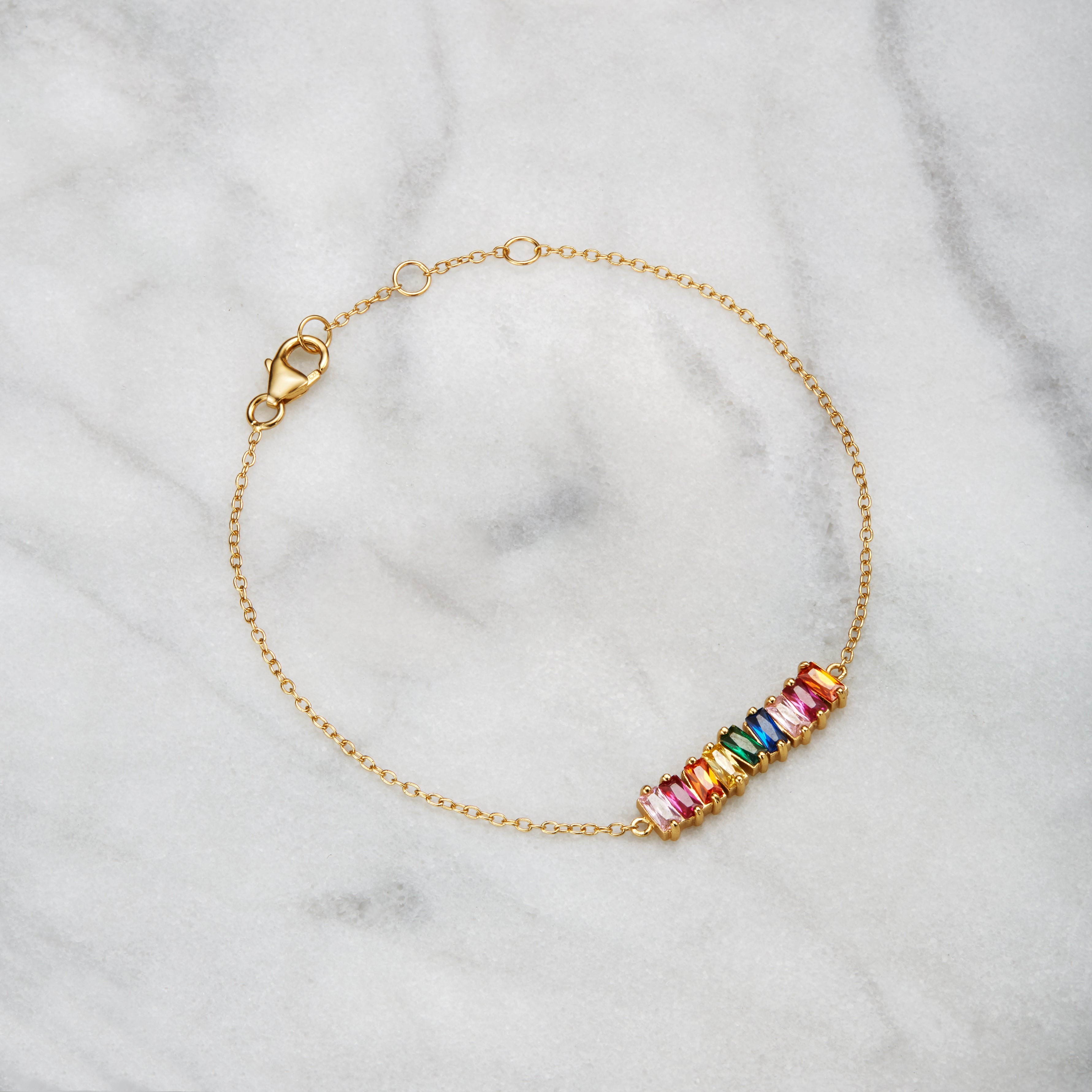 Gold rainbow gemstone cluster bracelet on a marble surface