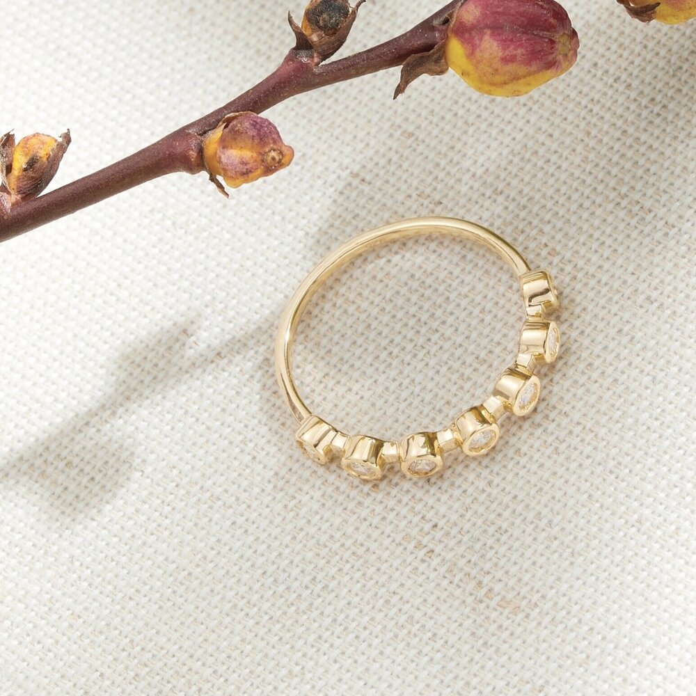 A gold diamond style round eternity ring on a cream woven surface