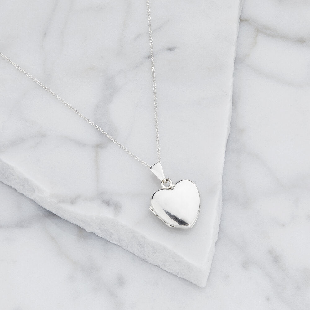 Silver small heart locket necklace on marble surfaces