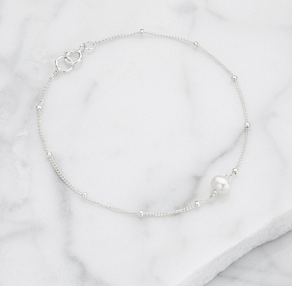Silver satellite pearl bracelet on a marble surface