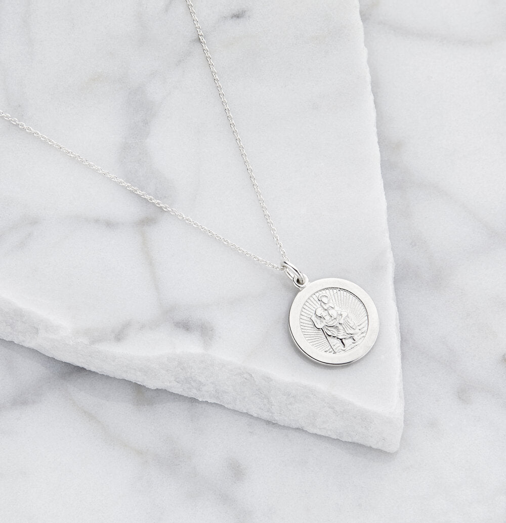 Silver small round St Christopher medallion necklace on marble surfaces