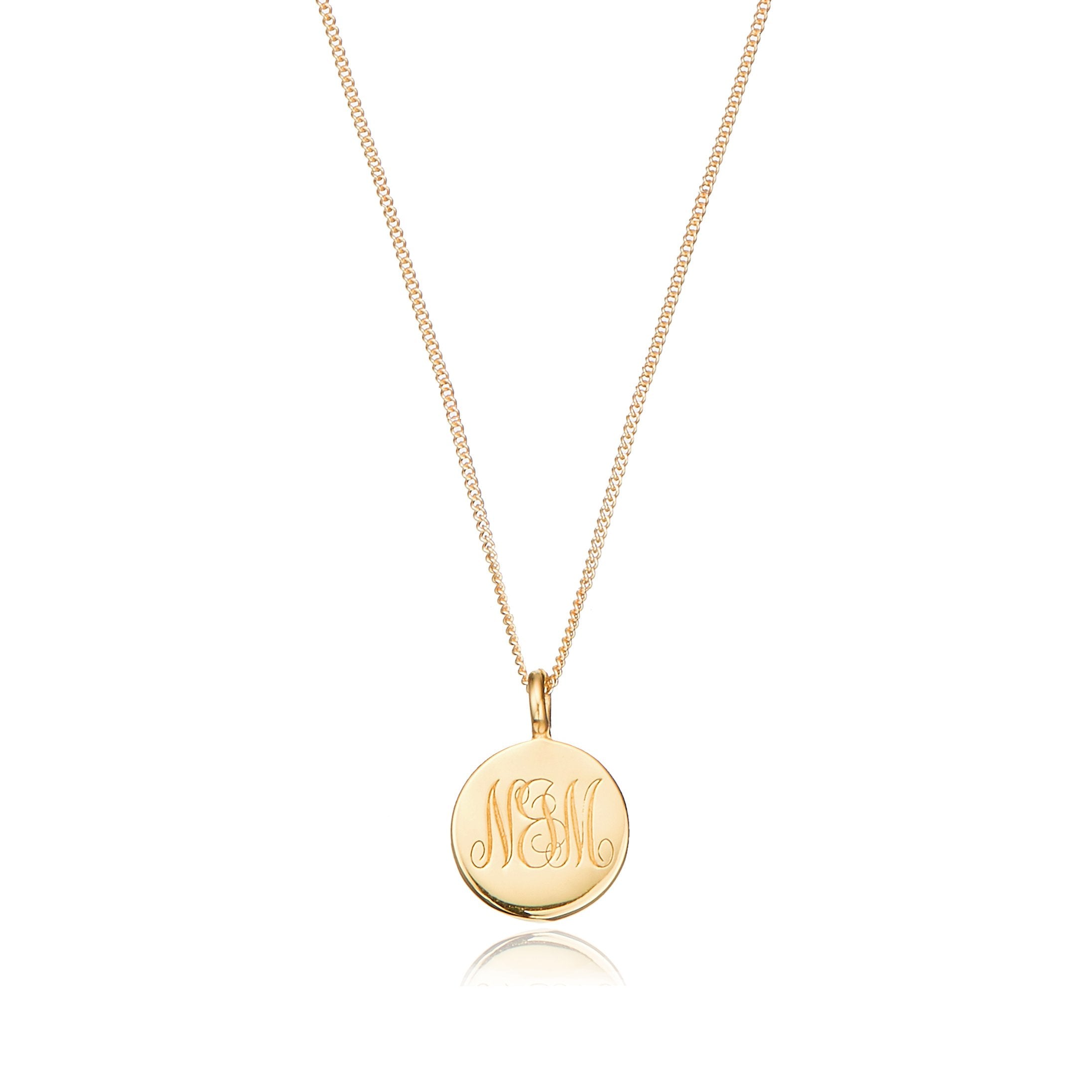 Gold large engraved disc necklace with N&M engraved on a white background