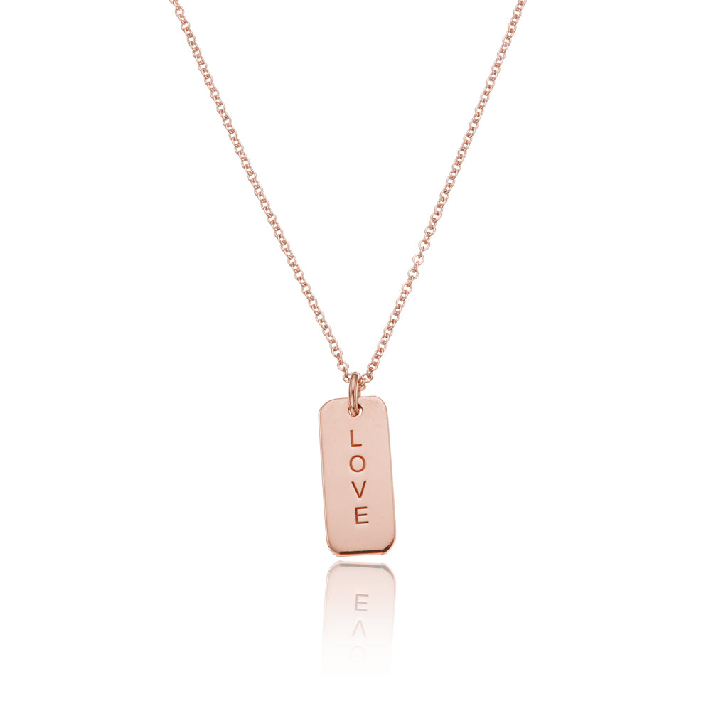 Rose gold personalised tag necklace with 'LOVE' engraved on it on a white background
