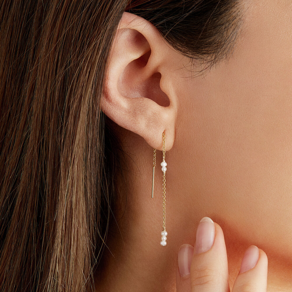 Gold mini pearl ear threader in one ear lobe