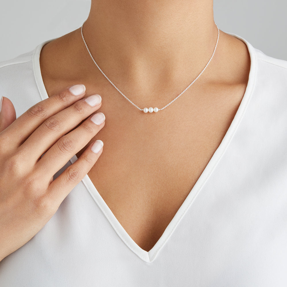 Silver cluster pearl choker around a neck with a white V-neck top