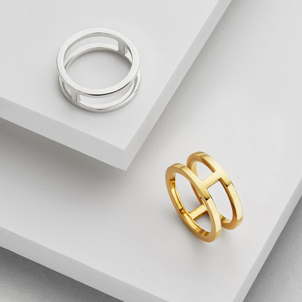 Gold double band ring and silver double band ring on marble surfaces