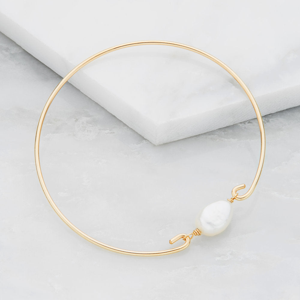 Gold large pearl bangle on marble surfaces