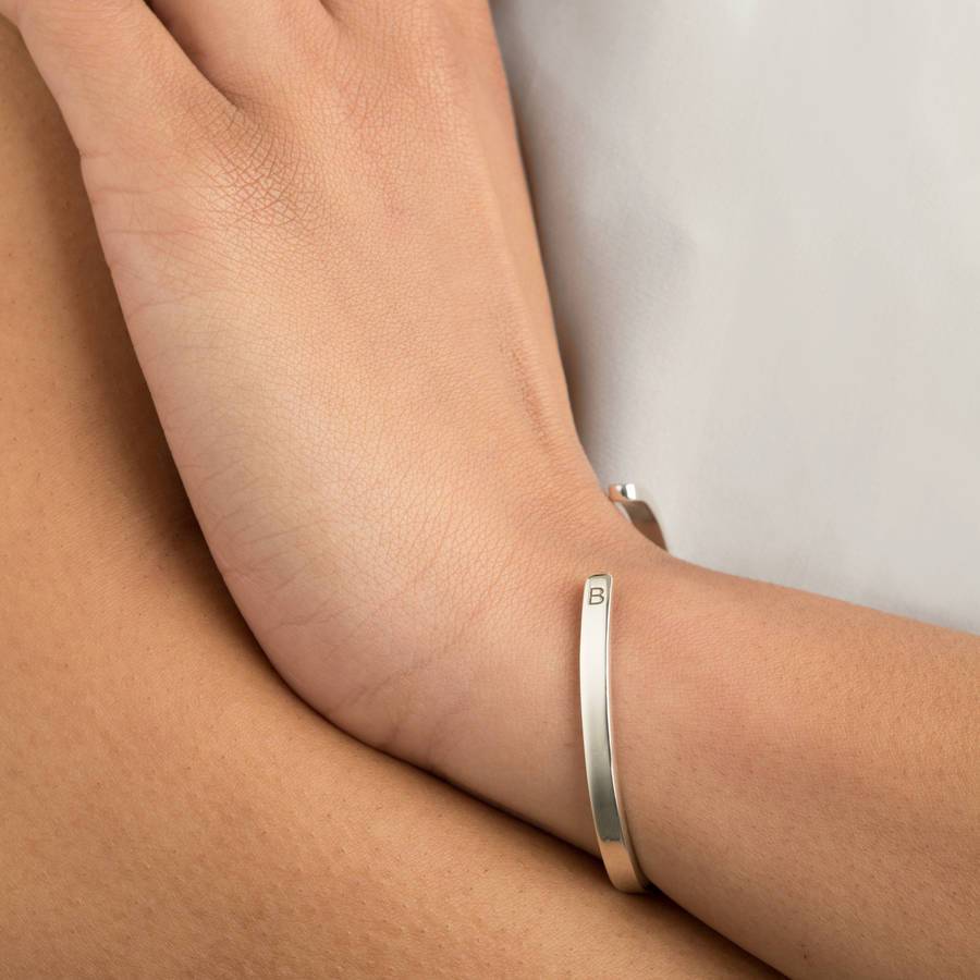 A silver thin engraved bangle with the letter 'B' engraved on a wrist