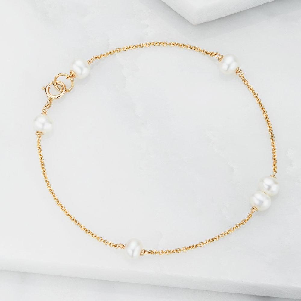 Gold six pearl bracelet on a marble surface