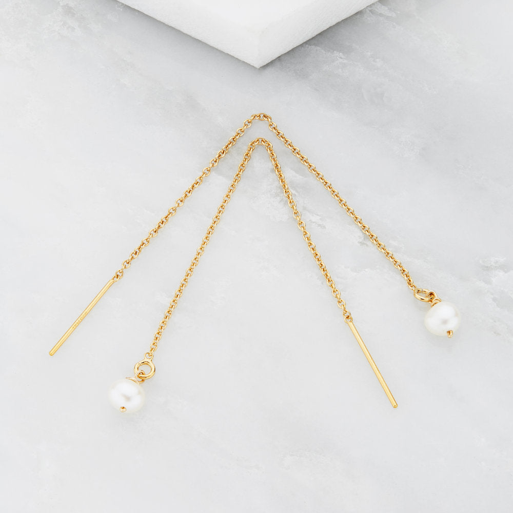 Gold pearl drop ear threaders on a marble surface